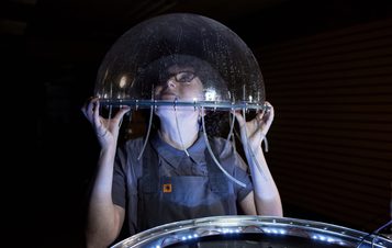 a person with their head inside a clear bubble-like plastic dome