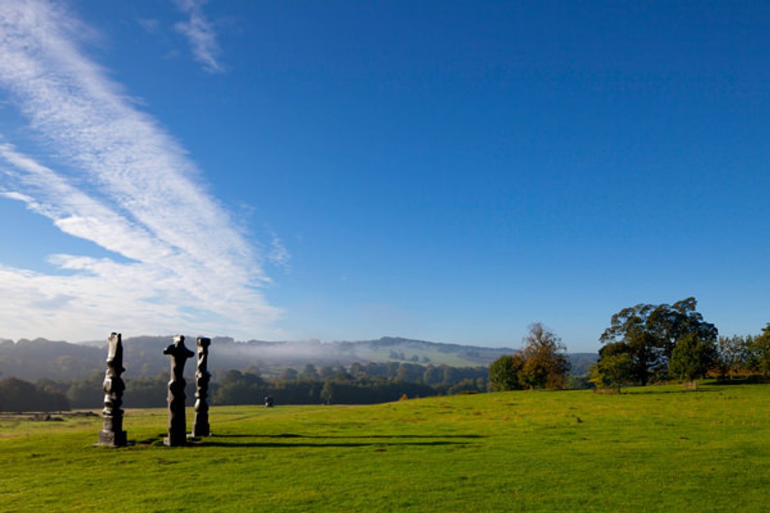 Three tall thin bronze sculptures looking out over the landscape