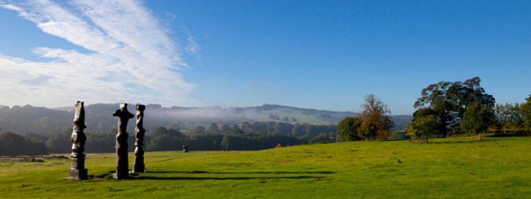 Three tall thin bronze sculptures looking out over the landscape
