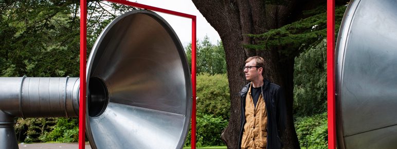 A man standing in between two giant silver tubes with red frames