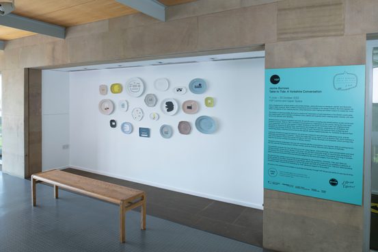 Twenty plates hung and exhibition text on wall of upper gallery space at YSP.