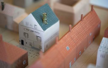 Miniature wooden painted terraced houses and a house.
