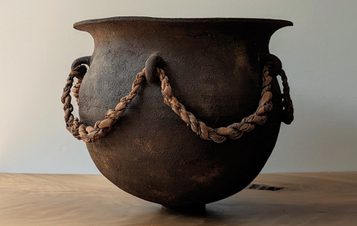 A carved wooden vessel with rope embellishments