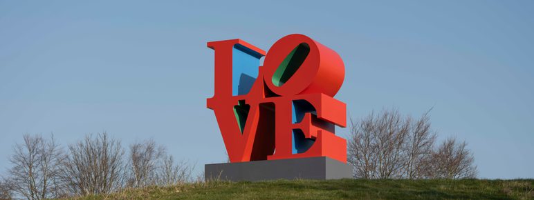 Red, blue and green LOVE sculpture on a grass mound at YSP.