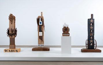 Four sculptures on a plinth in a gallery.