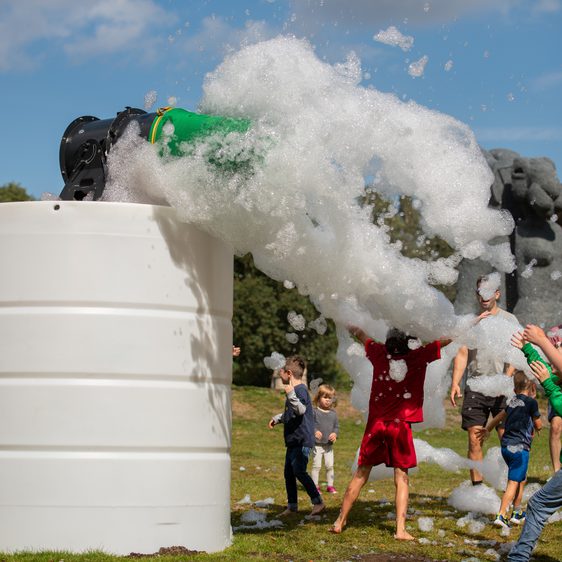 A group of people playing in a cloud of foam outdoors