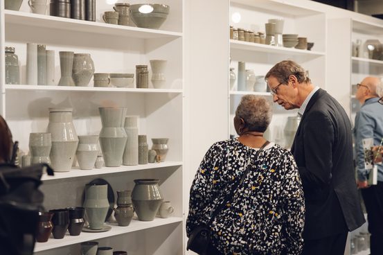 A black woman and white man looking a display of contemporary ceramics