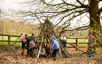 A group of children building a den out of sticks.