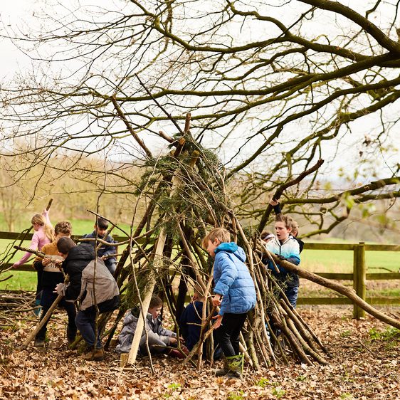 A group of children building a den out of sticks.