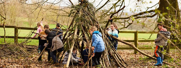 A group of children building a den out of sticks.