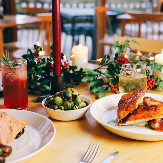 A table with plates of festive food and decorative foliage.