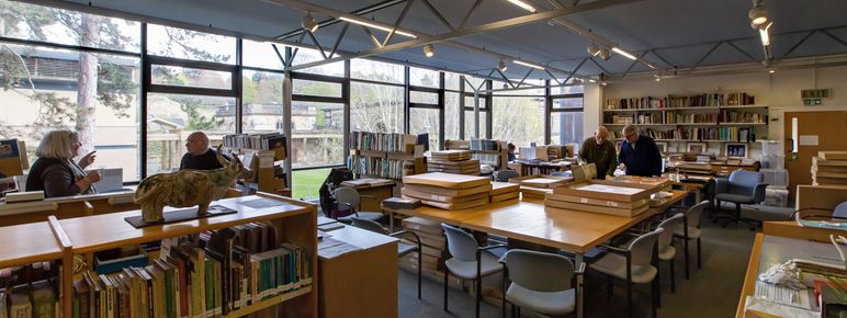 Four people stood amongst bookshelves and tables in the National Arts Education Archive.