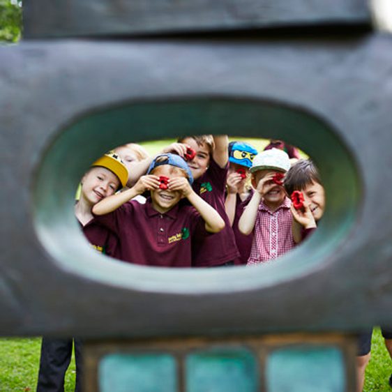 A group of young children looking through the eye of a sculpture.