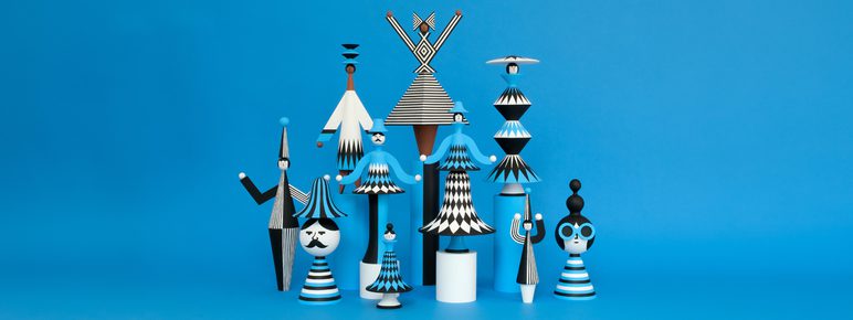 A group of black, white and blue painted wooden figures displayed against a blue background.