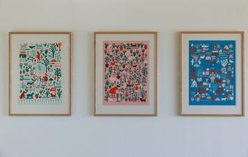 Three colourful framed screen prints displayed on a white wall.
