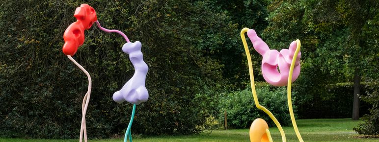 Two colourful sculptures of blobs attached to thin metal legs, displayed outdoors.