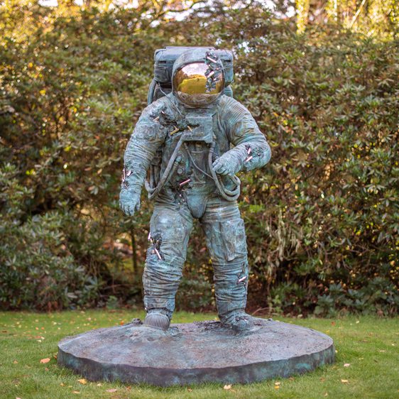 A bronze sculpture of an astronaut with crystal erosions coming out of the bronze.
