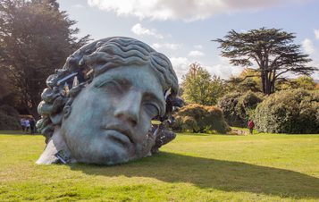 A large bronze sculpture of a woman's head, with eroded crystal sections.