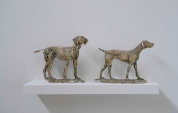 Two plaster models of dogs displayed on a shelf.