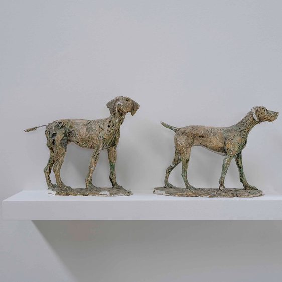 Two plaster models of dogs displayed on a shelf.