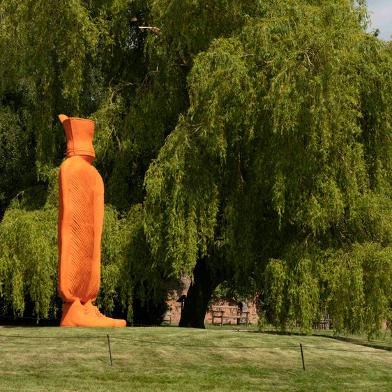 A giant orange hot water bottle on grass