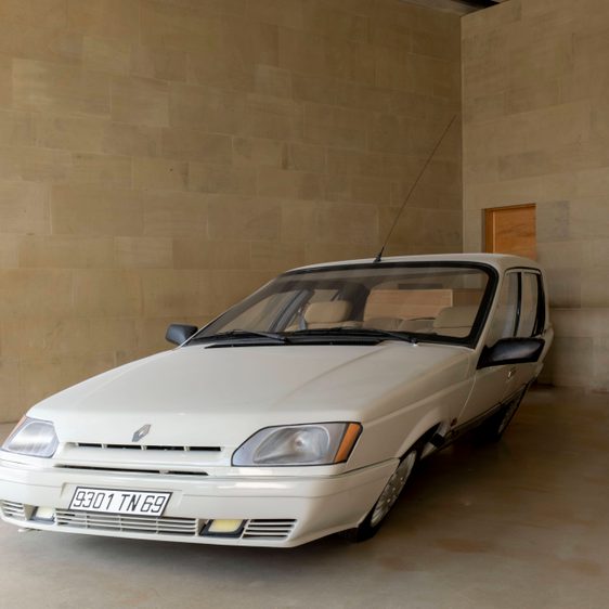 A white slanted car in a gallery space