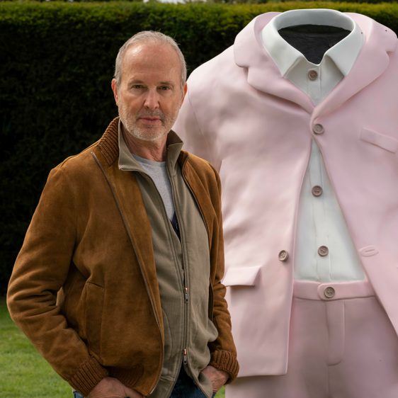 Man stood in front of sculpture of a pink suit