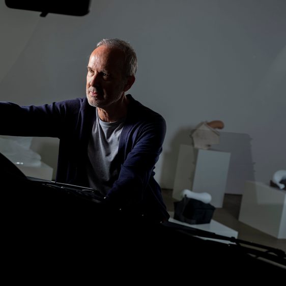 Man illuminated by light with sculptures in the background