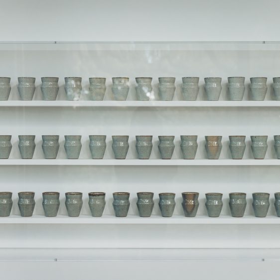 Three shelves filled with small ceramic vessels