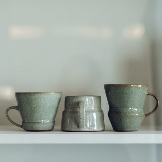 Three ceramic cups on a shelf