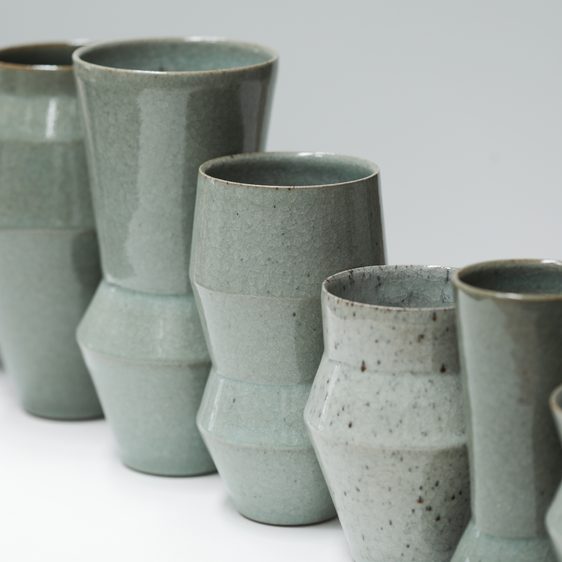 A diagonal row of green-toned ceramic vases