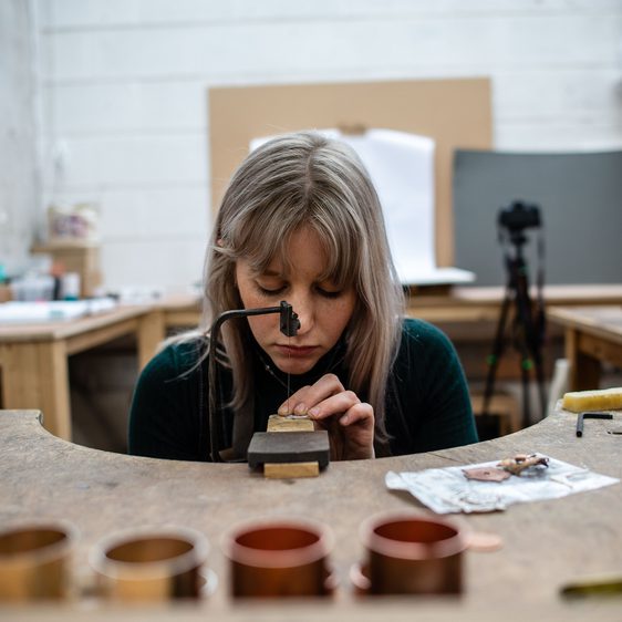 A woman working a wooden bench sawing wood.