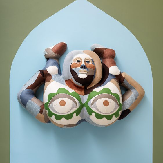 Felt sculpture against a wall of a person bearing their bottom