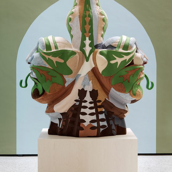 Felt sculpture of two heads back to back with their tongues sticking out