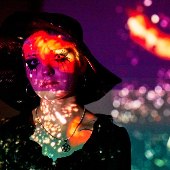 Women wearing a black hat and heavy black eye makeup.