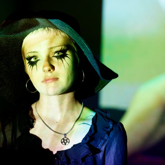 Women wearing a black hat and heavy black eye makeup.