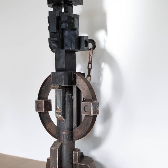 Black wooden sculpture with abstract facial features.