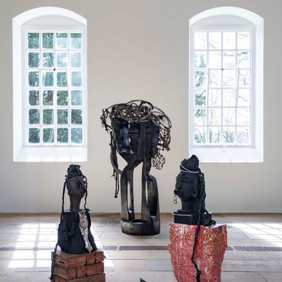 Three large sculptures indoors with two large windows in the background