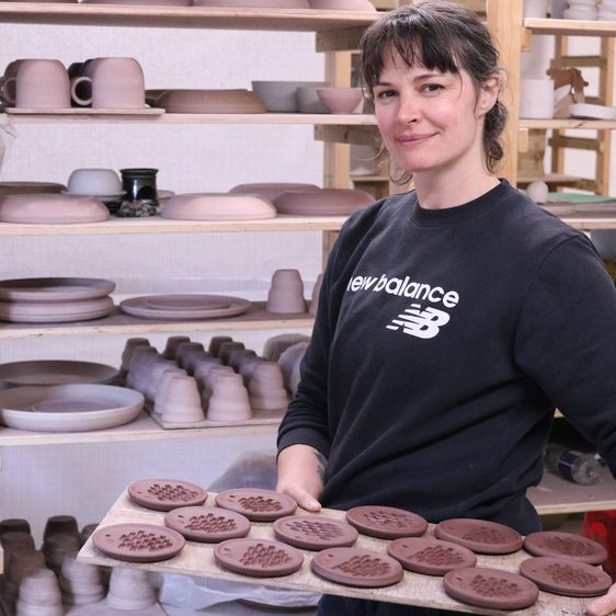 Woman holding a tray of unfired clay plates