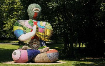 A seated humanoid figure covered in brightly coloured mosaic tiles