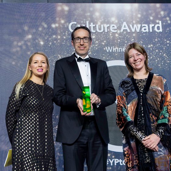 Man holding a trophy stands in between two women