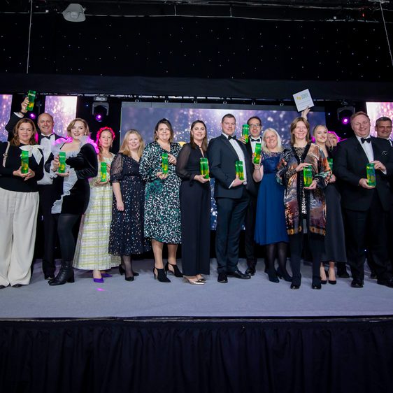 A large group of people holding trophies on a stage.