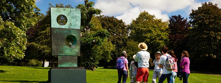 A group of people looking at contemporary sculpture outside.