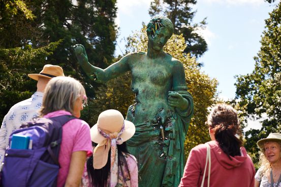 A group of people looking at the statue of a female figure.