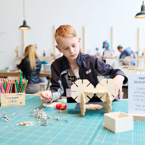 A child builds a sculpture our of interconnecting wooden pieces.