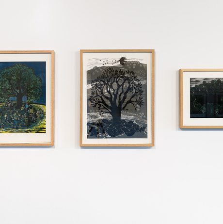 Three framed lino cut prints of landscapes on a white wall.
