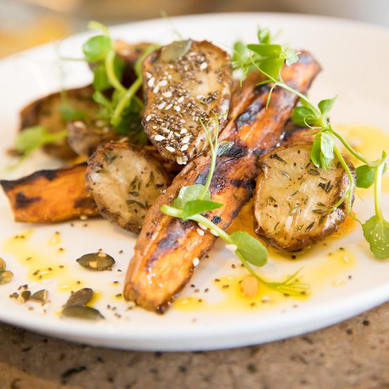 A plate of carrots and potatoes with pumpkin seeds and watercress.