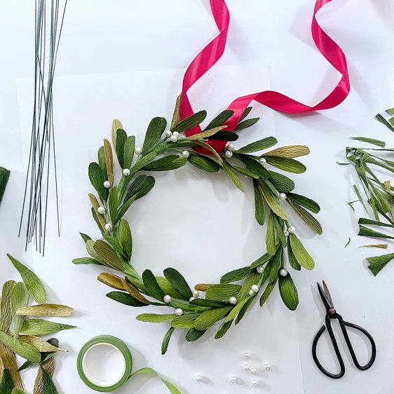 A circular paper wreath surrounded by tools and ribbons.