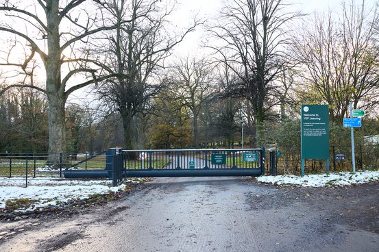 The Park Lane entrance to YSP, showing a road, green gate and signage.