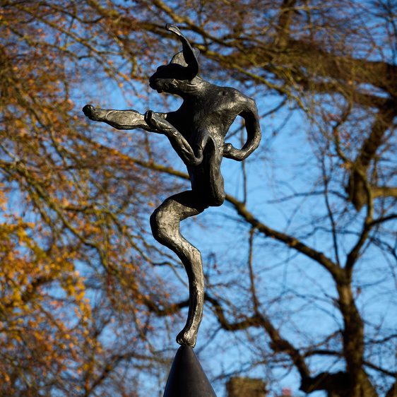 A sculpture of a hare balanced on the tip of an oversized anvil, displayed outdoors.